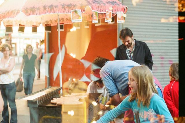 People moving around a sauce cart in what looks like a food market