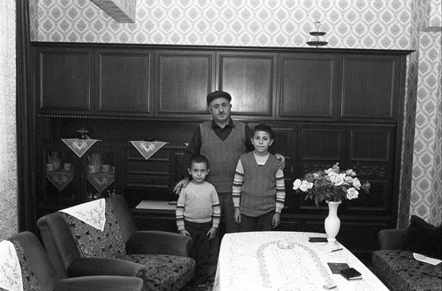 A man and two kids pose for the picture. The man is touching the kids shoulders.