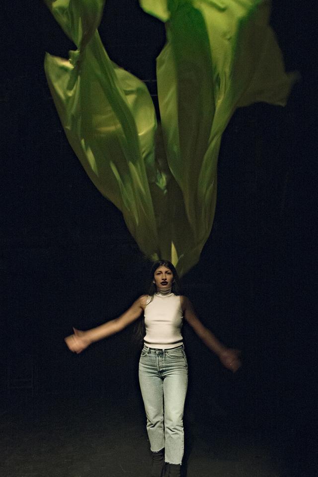 Woman standing with a green blanket on her back going to the air