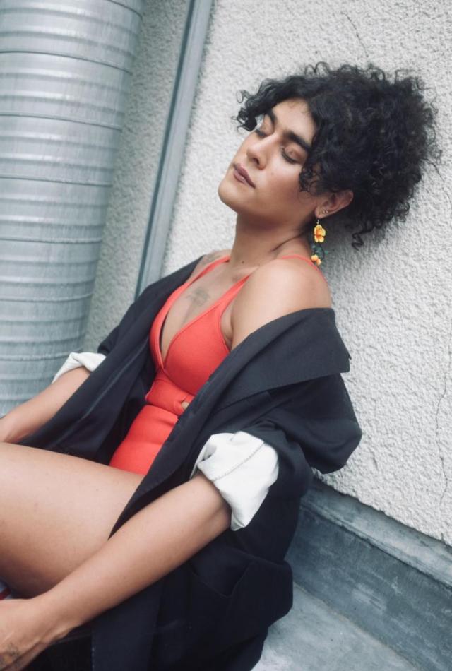 Artist sitting on the floor with red dress and black jacket