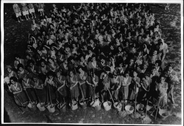 A group of women holding brooms and buckets