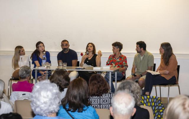 Acht Personen sitzen auf einem Präsentationstisch.