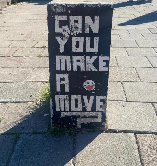 Wallpainting auf der Öffentlichkeit mit dem Satz "Can you make a move?" und ein Sticket daneben "Free Palestine"
