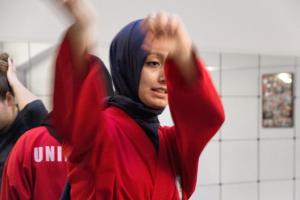 Woman wearing a red rope and headscarf with her fist in the air.